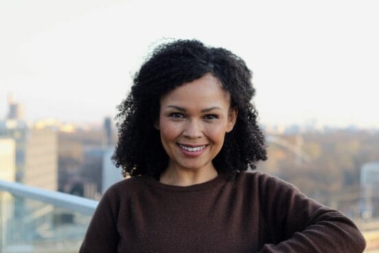 Journalistin Oyindamola Alashe steht im braunen Wollpullover auf einem Balkon