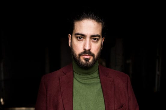 Mirza Odabaşı schaut in die Kamera im grünen Rollkragenpulli und weinrotem Jacket.